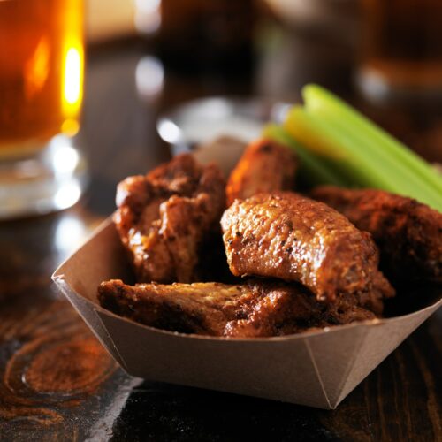 barbecue chicken wings with celery in basket on restaurant table