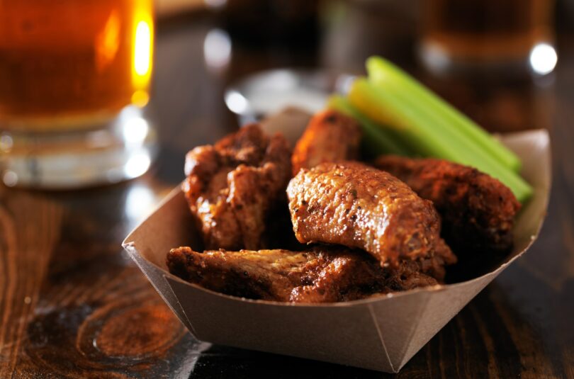 barbecue chicken wings with celery in basket on restaurant table