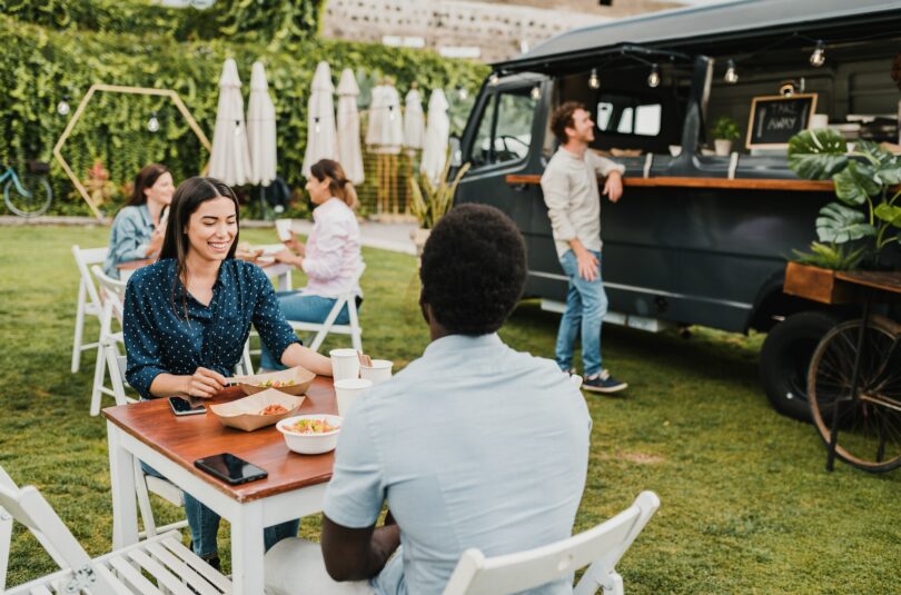 Diverse couple having lunch near food truck in park