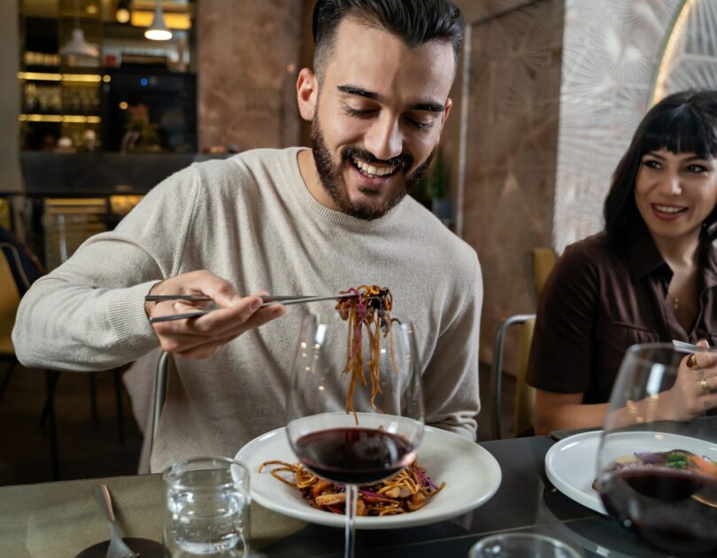 Happy couple at restaurant eating noodles at asian fusion food restaurant