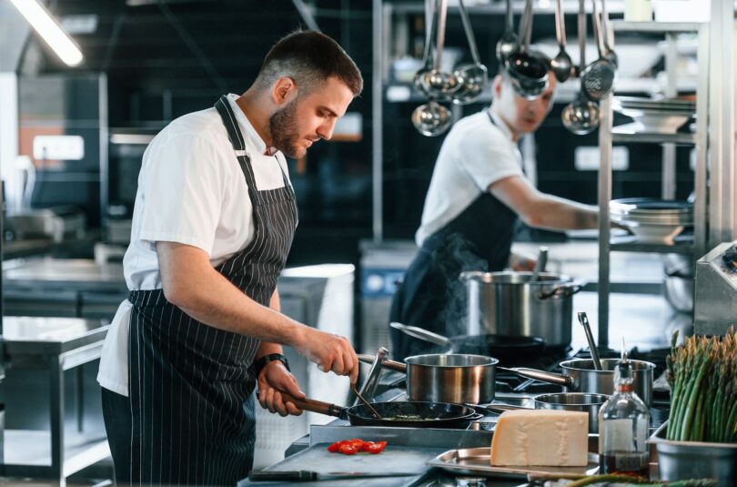 In uniform. Kitchen workers is together preparing the food