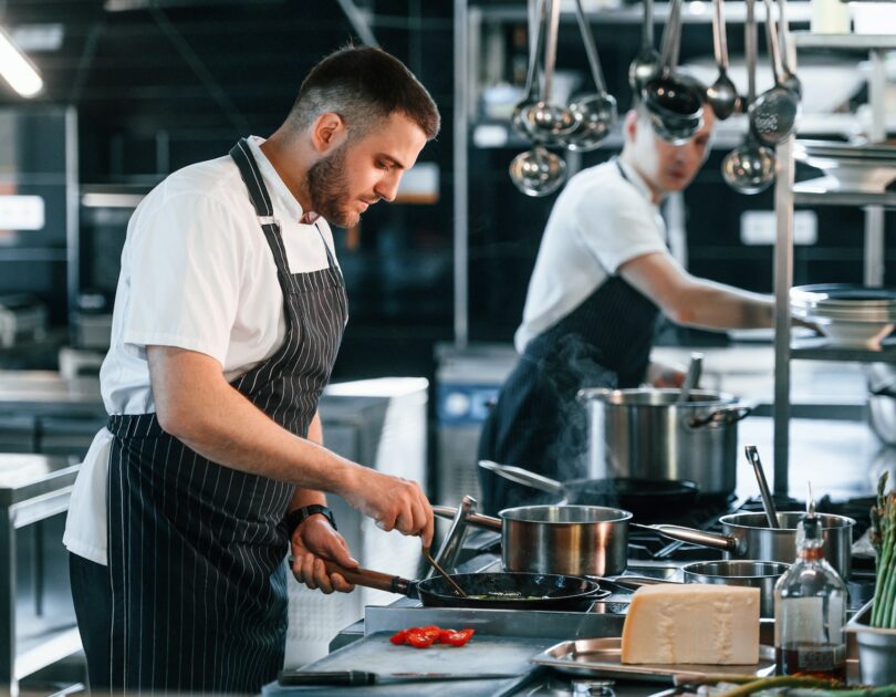 In uniform. Kitchen workers is together preparing the food